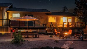 Un espace extérieur bien éclairé, aménagé en patio, avec une table à manger, des chaises et un foyer.