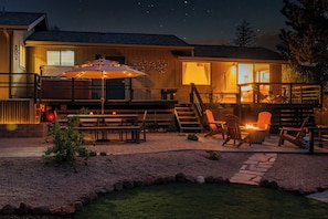 Un patio al aire libre bien iluminado con una mesa, sillas y un brasero.