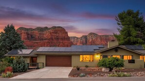 Une maison moderne dotée de panneaux solaires, d’un garage et d’un jardin bien entretenu à l’avant, agrémenté d’aménagements paysagers.