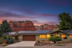 Una casa moderna con paneles solares, un garaje y un jardín delantero cuidado con jardinería.
