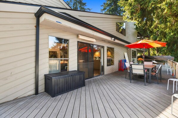 A deck with outdoor furniture and a covered area with a red umbrella.