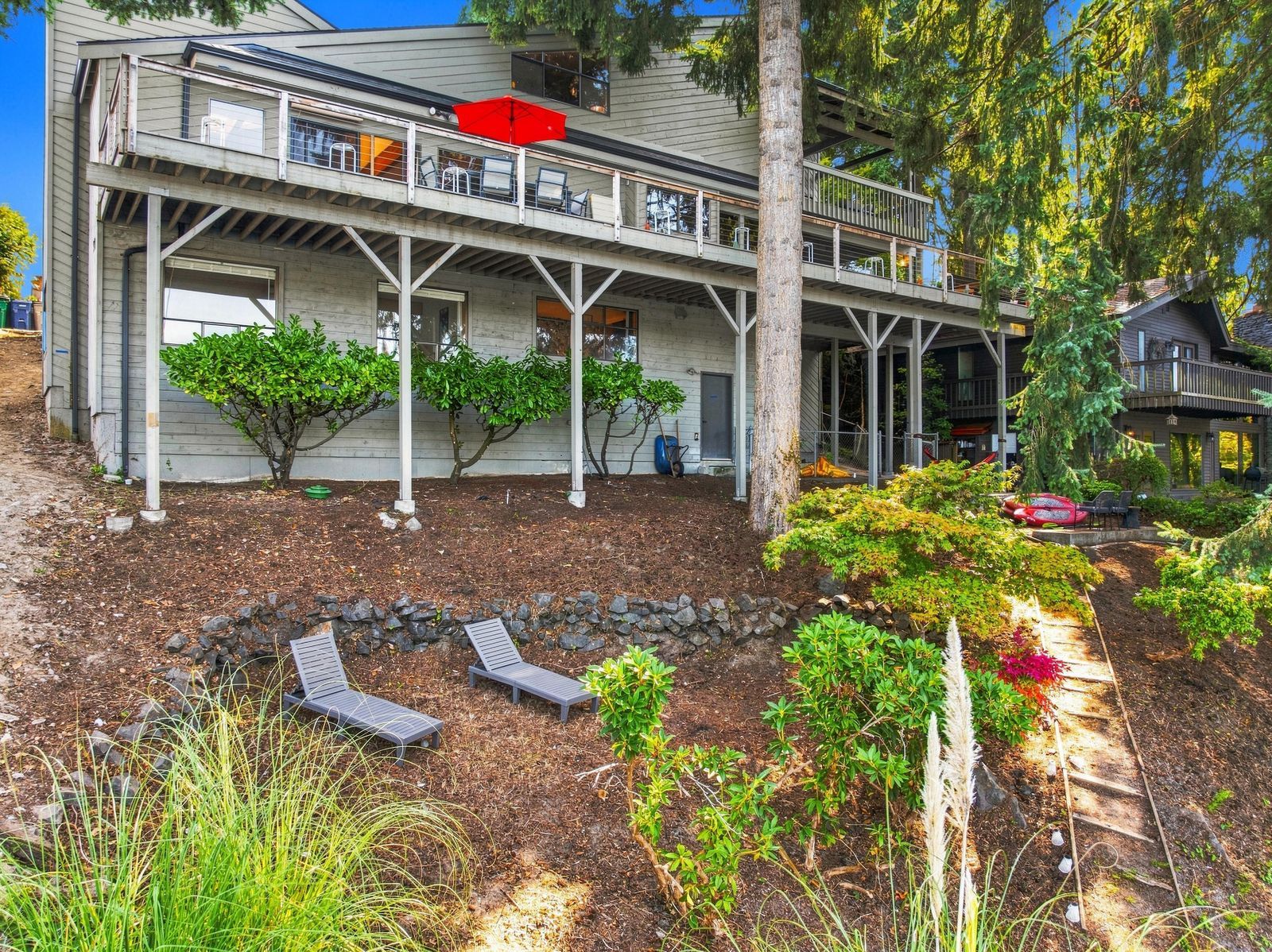 A two-story house with a covered porch, outdoor seating, and a landscaped garden.