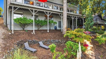 A two-story house with a covered porch, outdoor seating, and a landscaped garden.