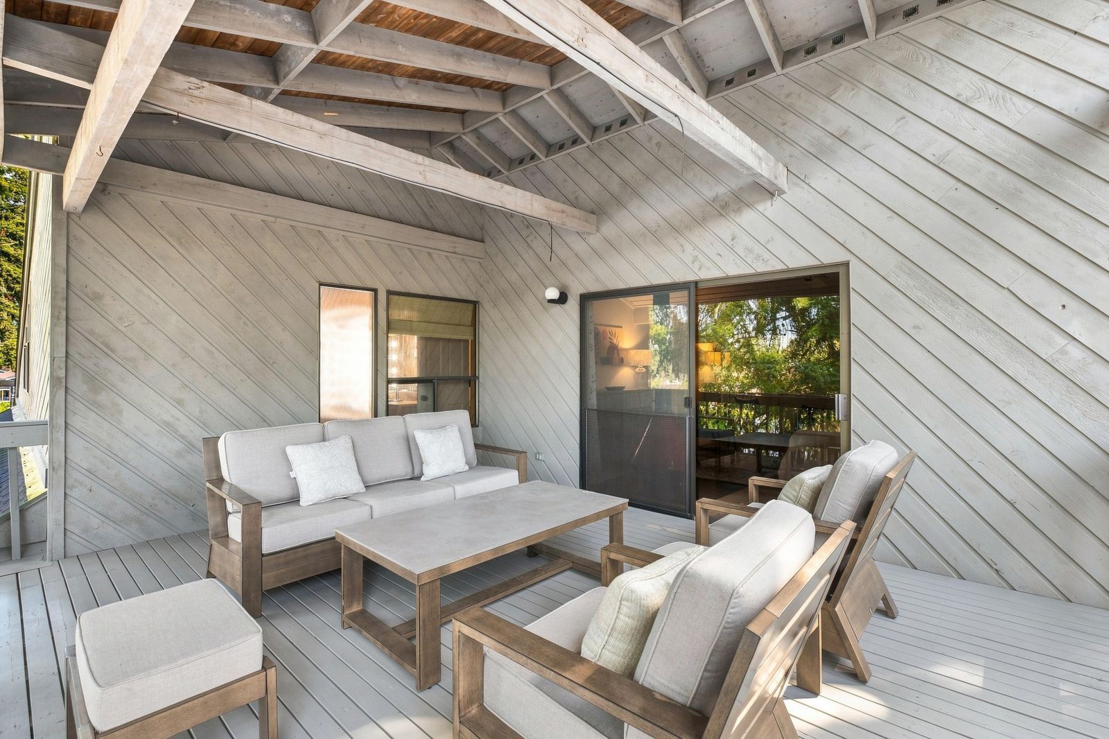Eine Terrasse im Freien mit einer Couch, Sesseln und einem Tisch.