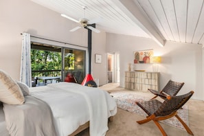 A bedroom with a bed, a chair, a fireplace, and a view of the outdoors. - Lake House Retreat w/Sauna, golf course, 30 min 2 Seattle, game room, water toys (Federal Way)