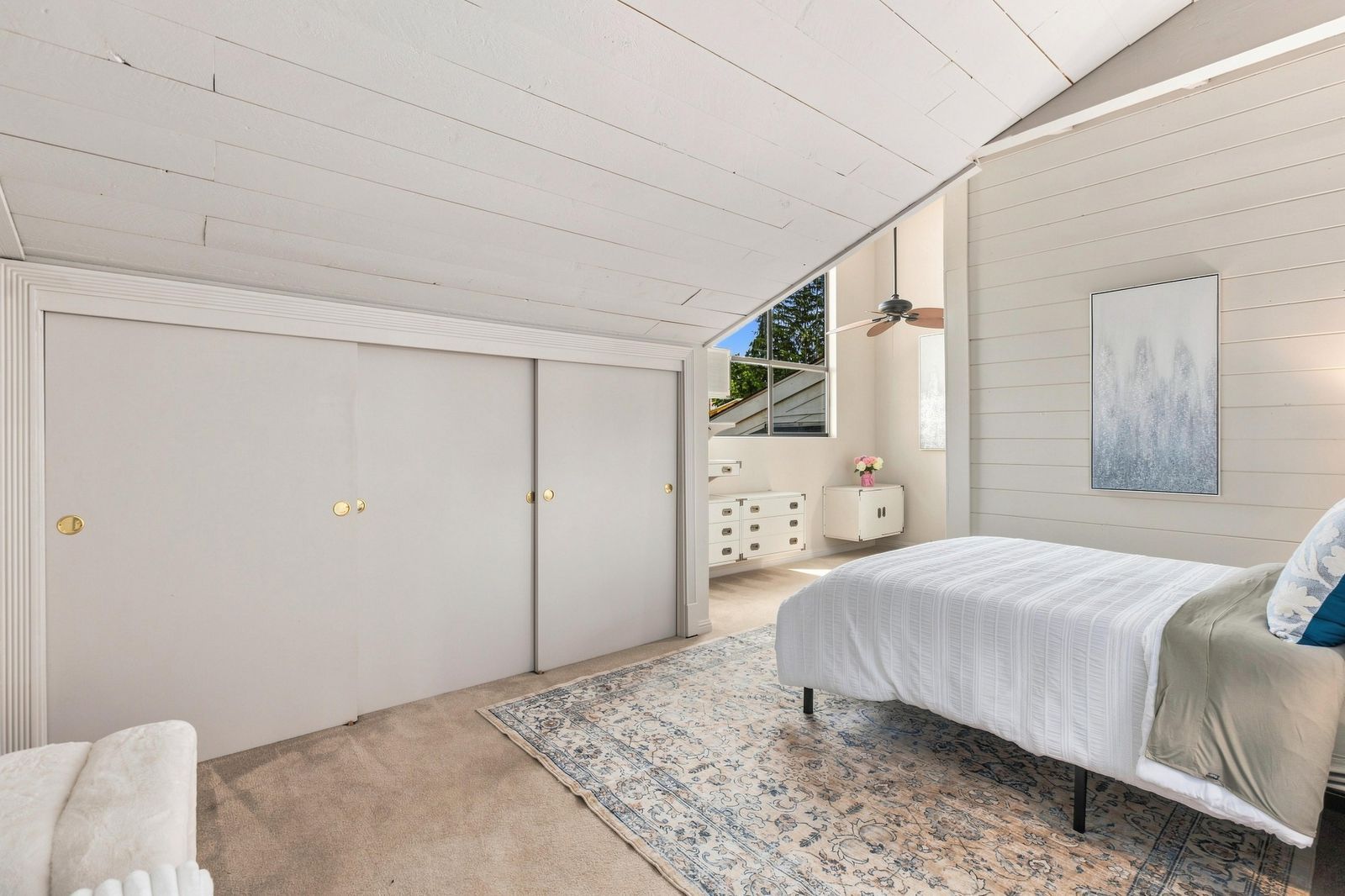 A bedroom with a bed, a dresser, a window, and a ceiling fan.