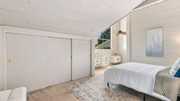 A bedroom with a bed, a dresser, a window, and a ceiling fan.
