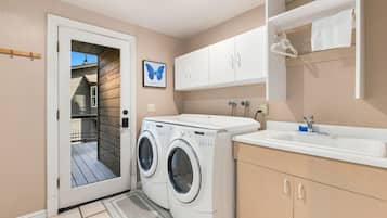Une buanderie équipée d’un lave-linge, d’un évier et de placards.