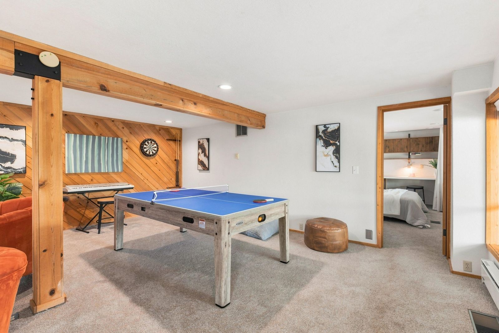 A room with a ping pong table, a dartboard, and a piano.