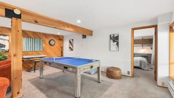 A room with a ping pong table, a dartboard, and a piano.