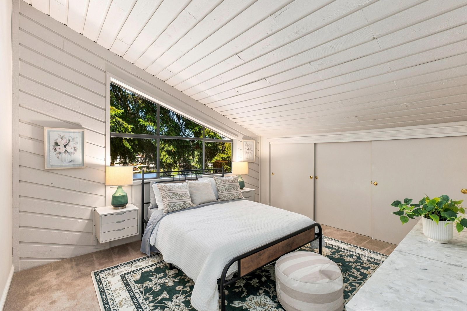 A bedroom with a bed, nightstands, a window, a wardrobe, and a potted plant.