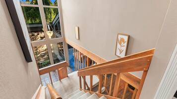 Un escalier avec des rampes en bois menant à un balcon d’où l’on peut admirer la verdure.
