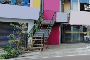 A staircase leading to a hotel entrance with a closed shutter door and a sign indicating it is a company-serviced hotel. - Hotel O Neredmet Road (Hyderabad)