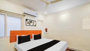 Una habitación de hotel con cama, ventilador de techo, aire acondicionado y ventana.