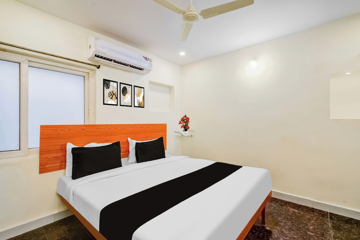 A hotel room with a bed, a ceiling fan, an air conditioning unit, and a window.