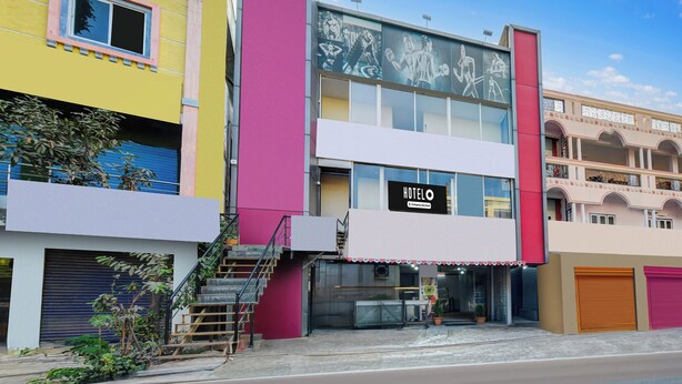 Un hotel con un llamativo letrero que dice 'HOTEL', una escalera que conduce a la entrada y un cielo despejado.