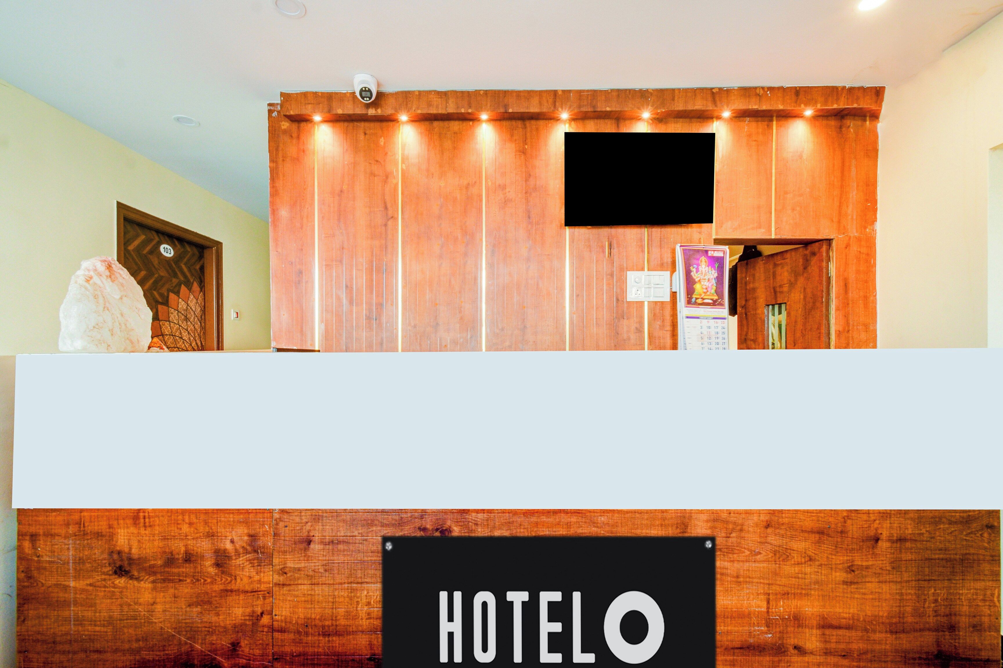 Una reception con finitura in legno, una targa con la scritta 'HOTEL' e una telecamera di sicurezza sopra.