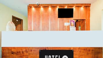Una reception con finitura in legno, una targa con la scritta 'HOTEL' e una telecamera di sicurezza sopra.