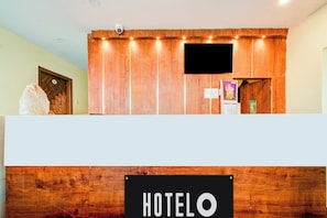 A reception desk with a wooden finish, a sign reading 'HOTEL', and a security camera above. - Hotel O Neredmet Road (Hyderabad)