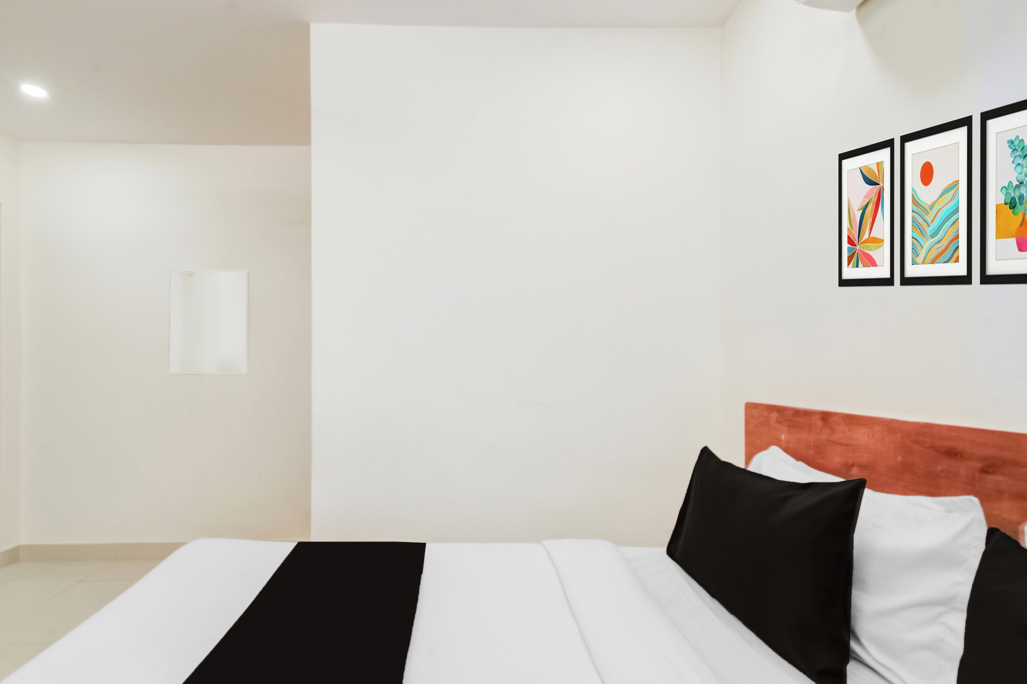 A hotel room with a bed, a headboard, and three framed artworks on the wall.