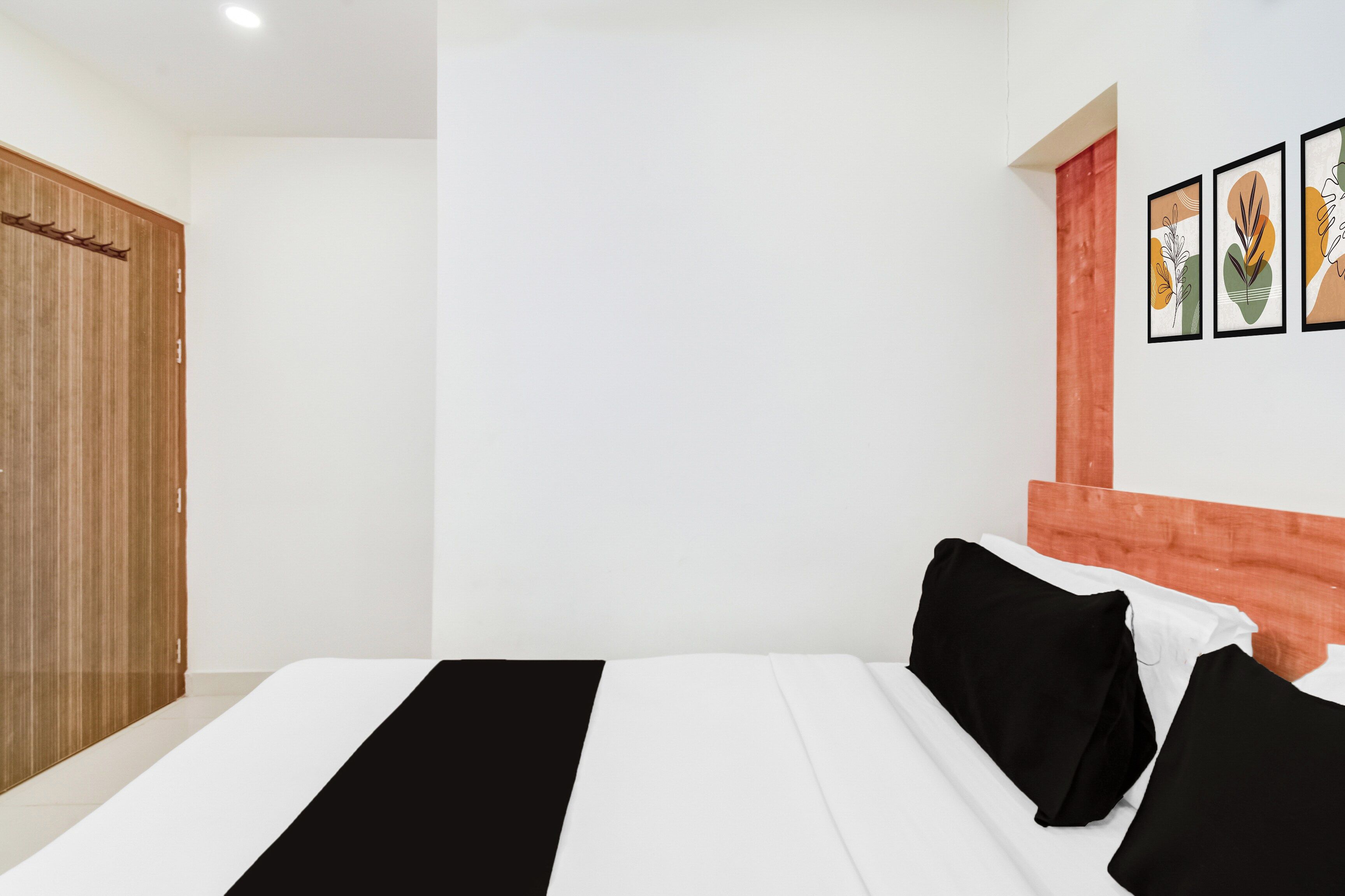 Una camera d'albergo con un letto, un armadio in legno e una parete decorata con quadri.