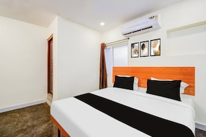 A hotel room with a bed, a window with curtains, an air conditioning unit, and a wall with framed artwork. - Hotel O Neredmet Road (Hyderabad)