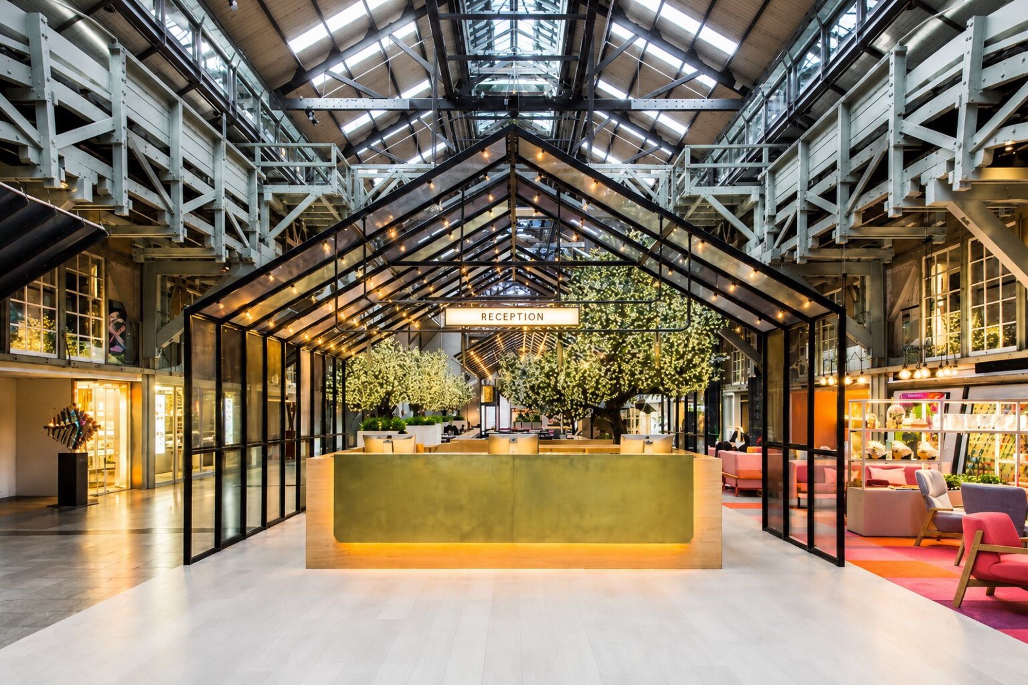 A reception area with a central desk, glass walls, and a high ceiling with metal beams.