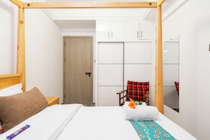 Une chambre à coucher comprenant un lit, une tête de lit en bois, une table de chevet, une chaise, une armoire et un miroir.