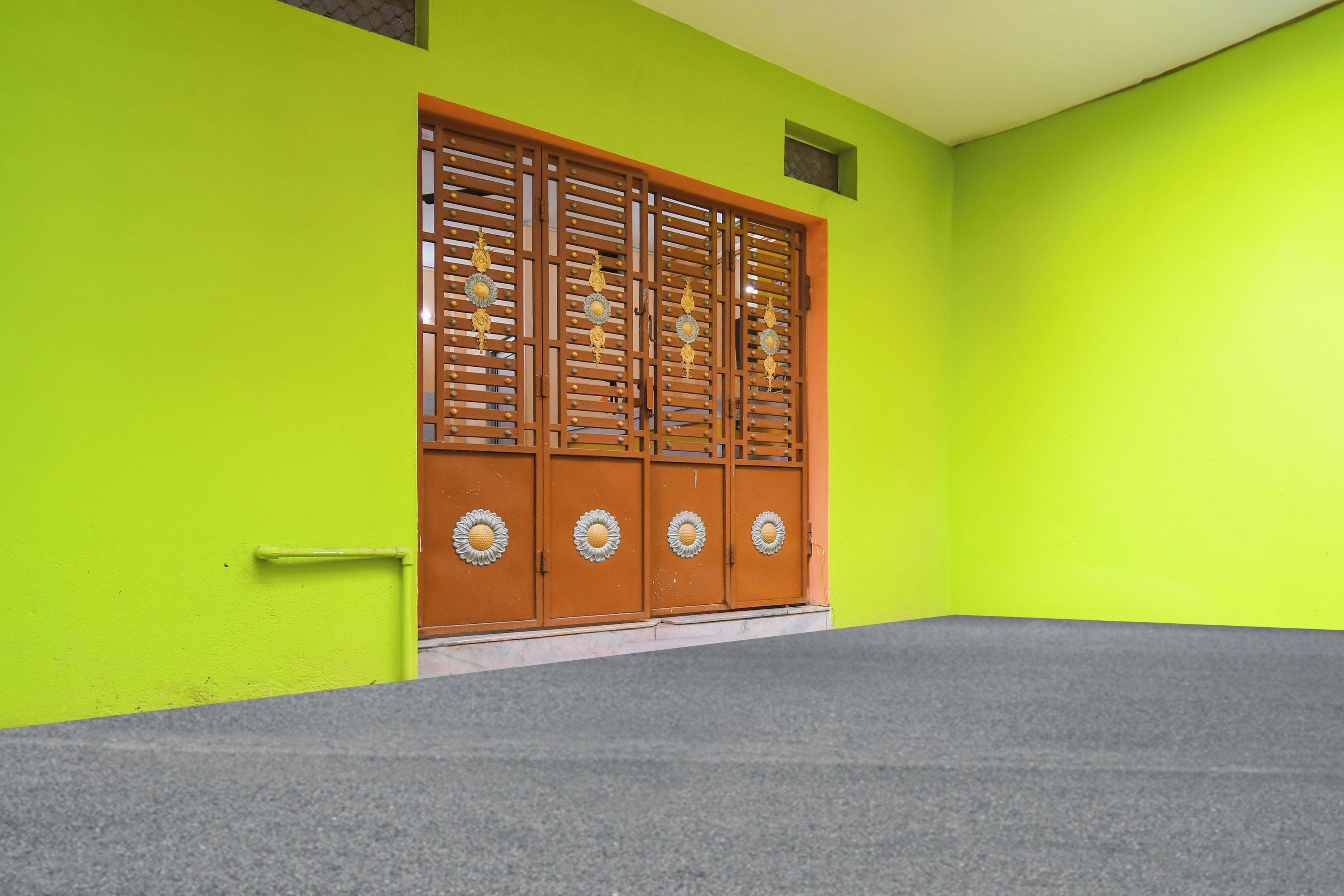 A building with a bright green exterior wall and a large wooden door with decorative metal elements.