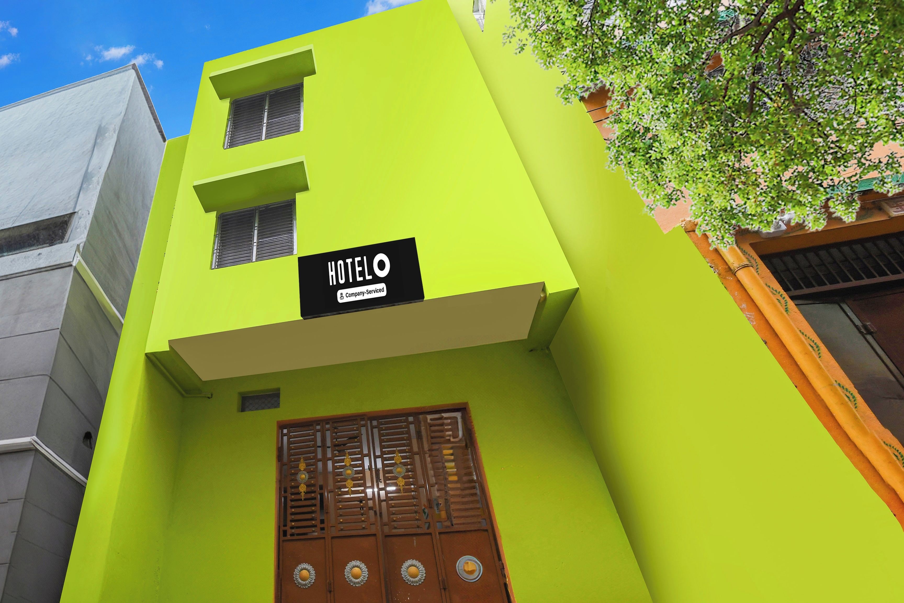 A building with a bright green facade, a sign indicating it's a hotel, and a wooden door with a window.