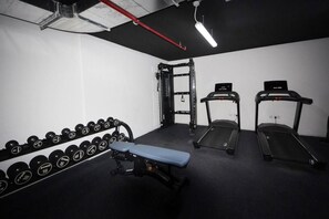 A gym with weightlifting equipment, treadmills, and dumbbells. - Bloomfields 1BR Duplex in Raha Lofts 2  (Abu Dhabi)
