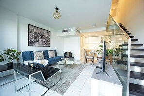 Una sala moderna con un sofá, una mesa de centro y un cuadro de un paisaje urbano.