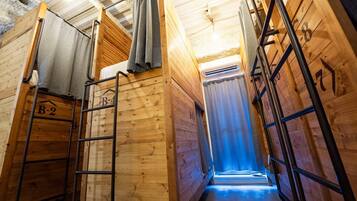 A wooden interior with bunk beds, a ladder, and a visible air conditioning unit.