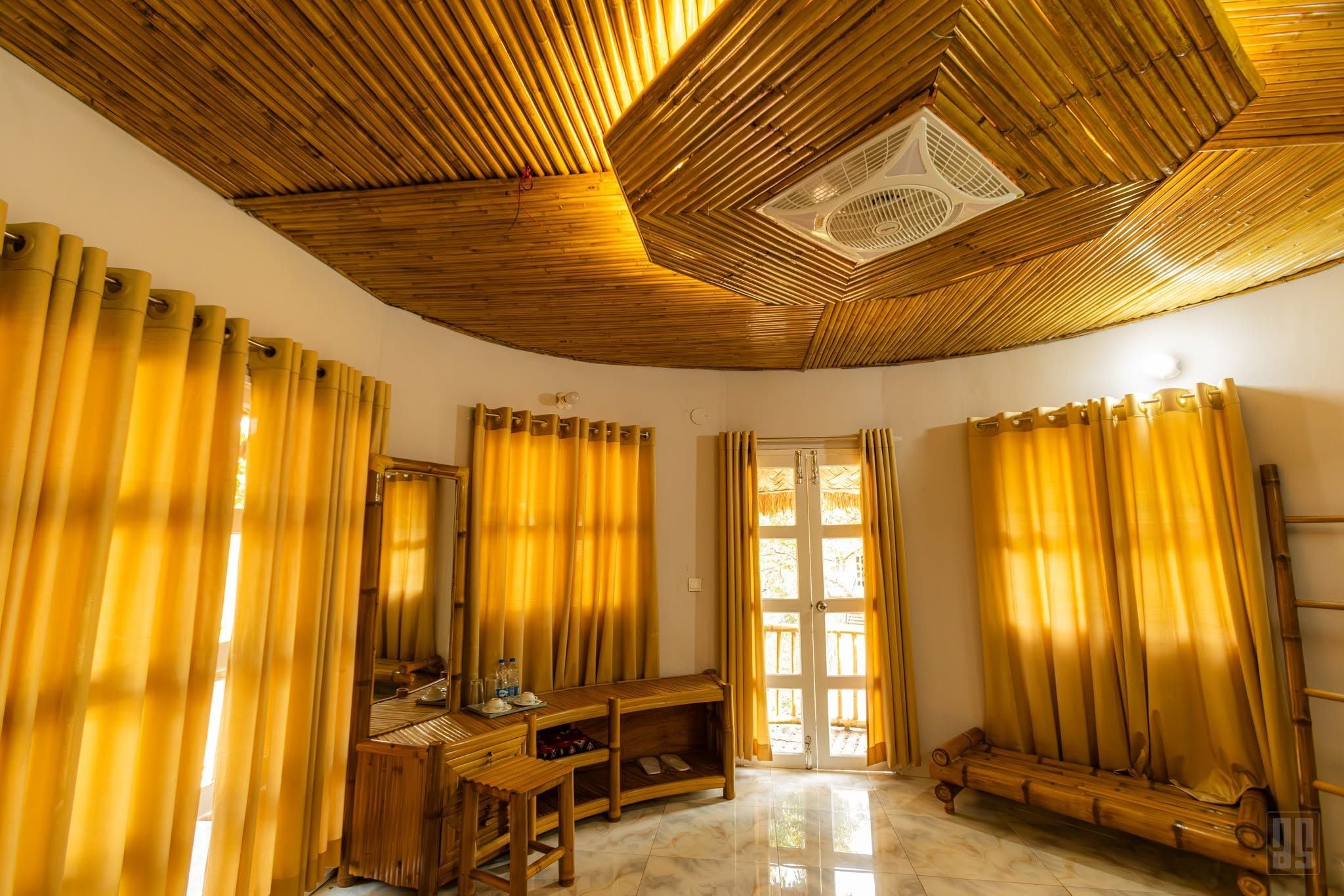 A room with a bamboo ceiling, a wooden bench, a mirror, and a door leading outside.