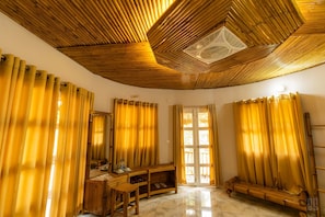 Una habitación con techo de bambú, un banco de madera, un espejo y una puerta que da al exterior.
