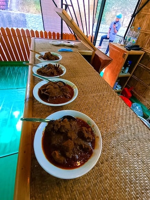 Un comedor con una mesa larga dispuesta para varias personas, que incluye un mantel tejido y una variedad de platos.