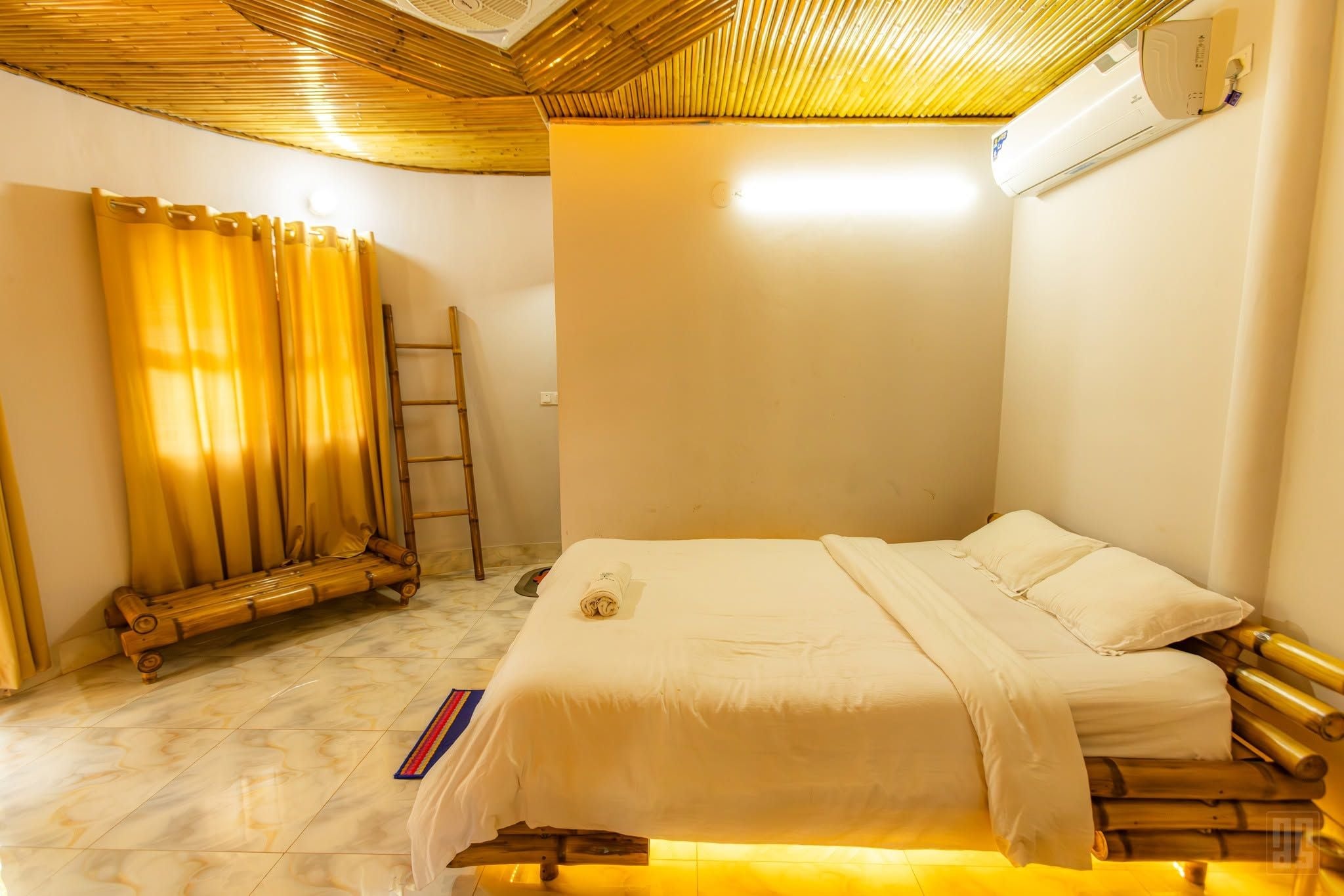 A room with a bed, a bench, a ladder, and a wall-mounted air conditioner.