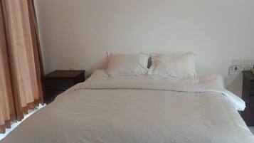 A bed with white bedding, a wooden ceiling, and two wall-mounted light fixtures.