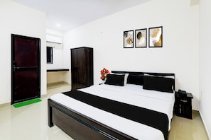 Una habitación de hotel con cama, armario, escritorio y teléfono.
