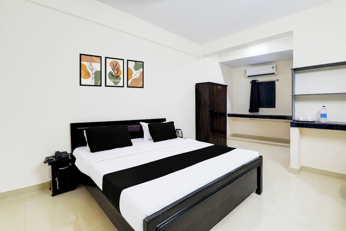 Una habitación de hotel con cama, armario, escritorio con silla y ventana con cortinas.