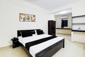 Una habitación de hotel con cama, armario, escritorio con silla y ventana con cortinas.