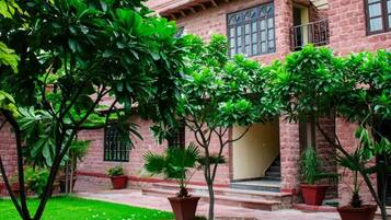 A building with a brick facade, a staircase leading to a door, and potted plants around the entrance.