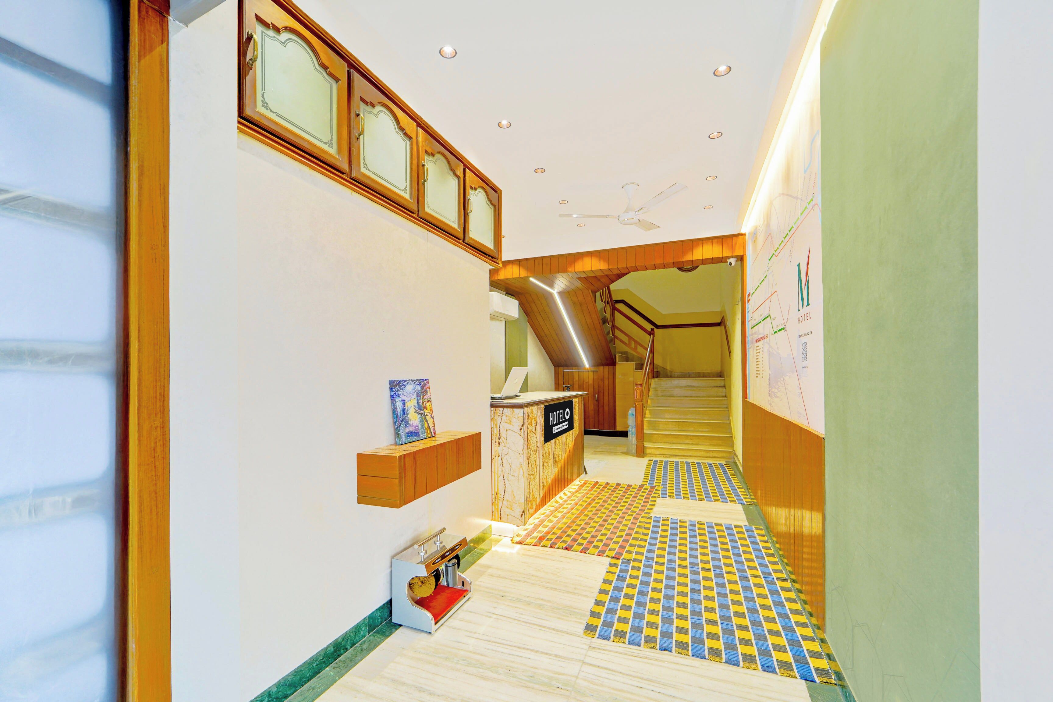 A hotel hallway with a marble floor, a reception desk, and a staircase leading to another floor.