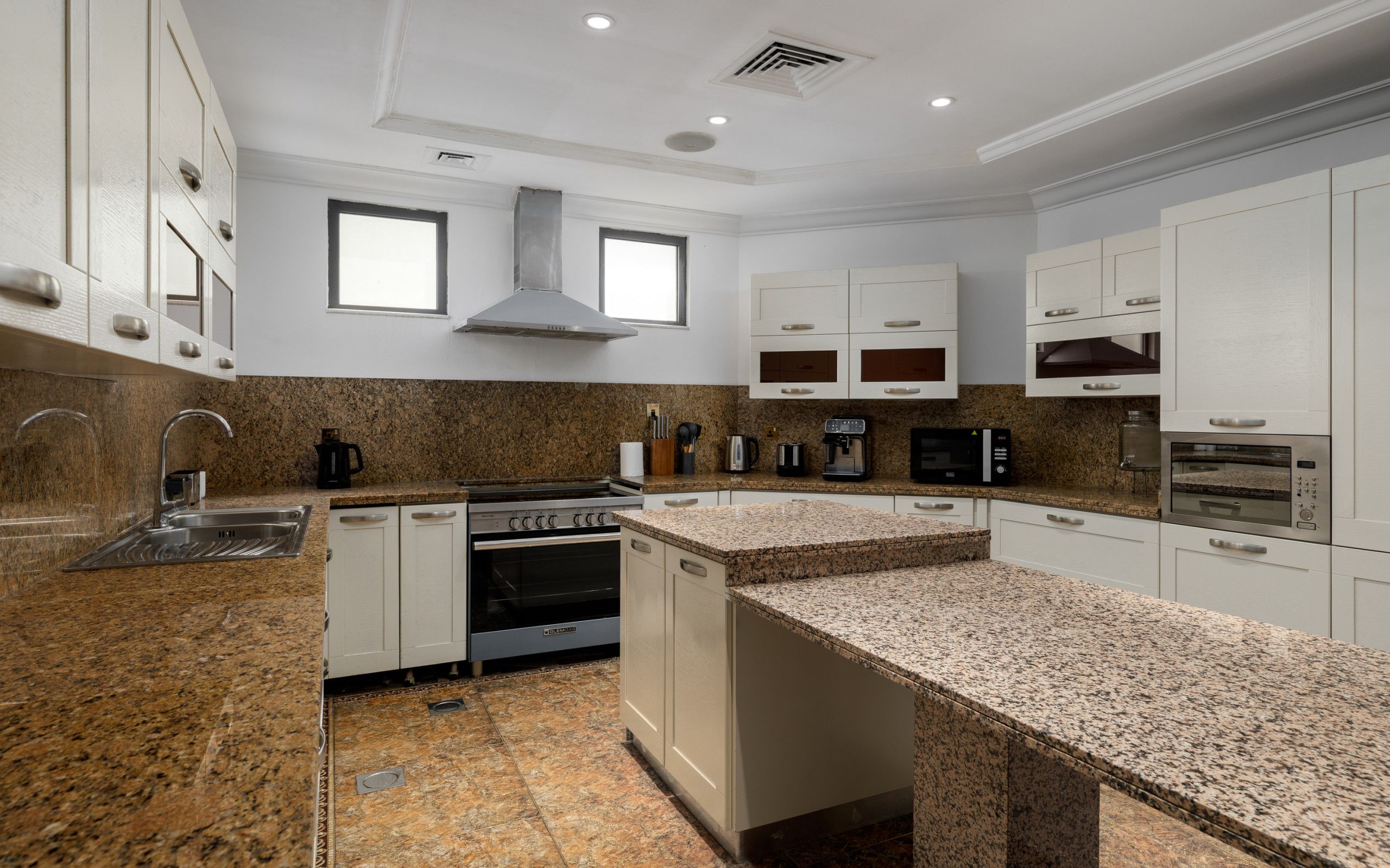 A modern kitchen with granite countertops, stainless steel appliances, and white cabinetry.