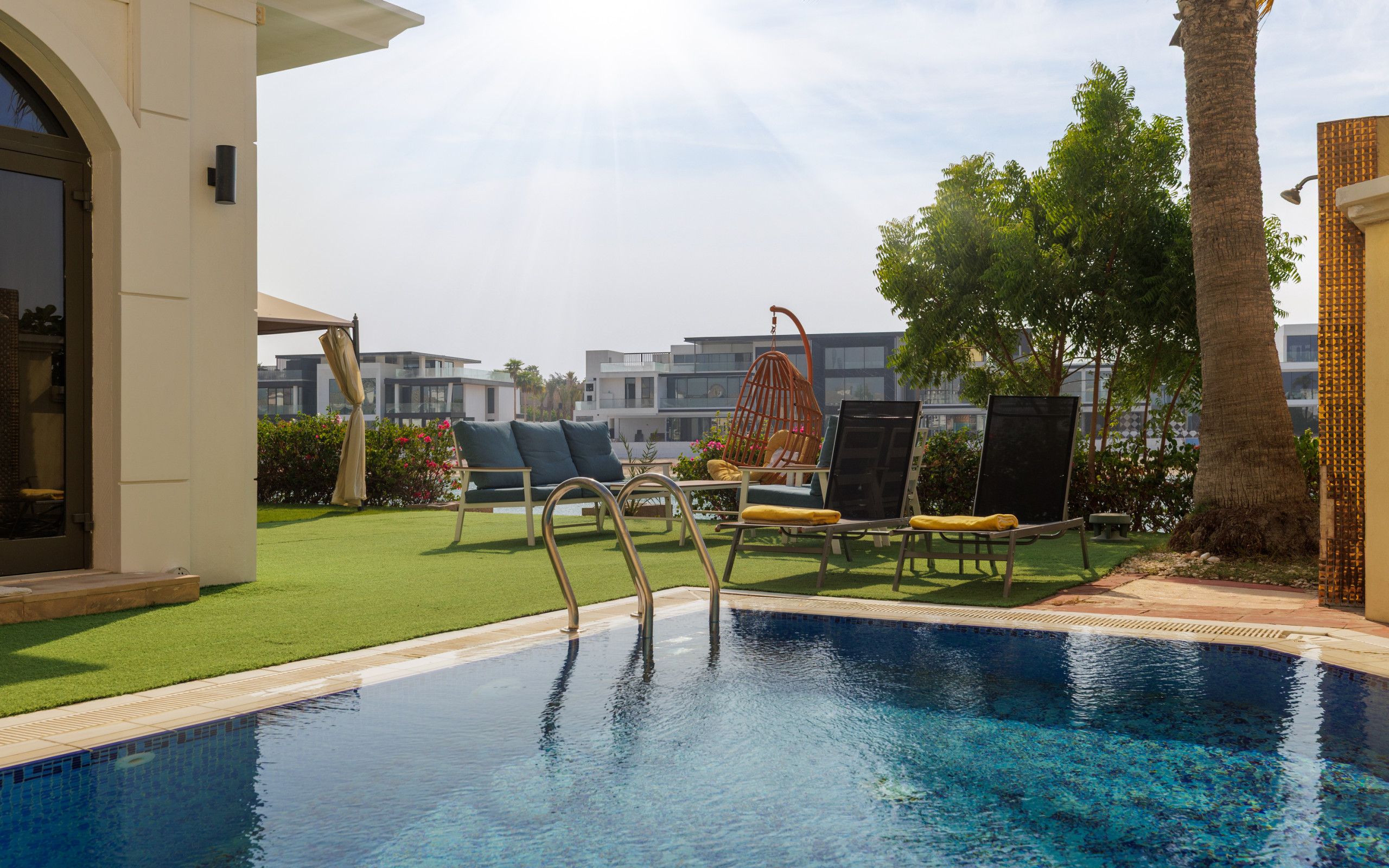 Une piscine avec des chaises longues et un espace de détente abrité.
