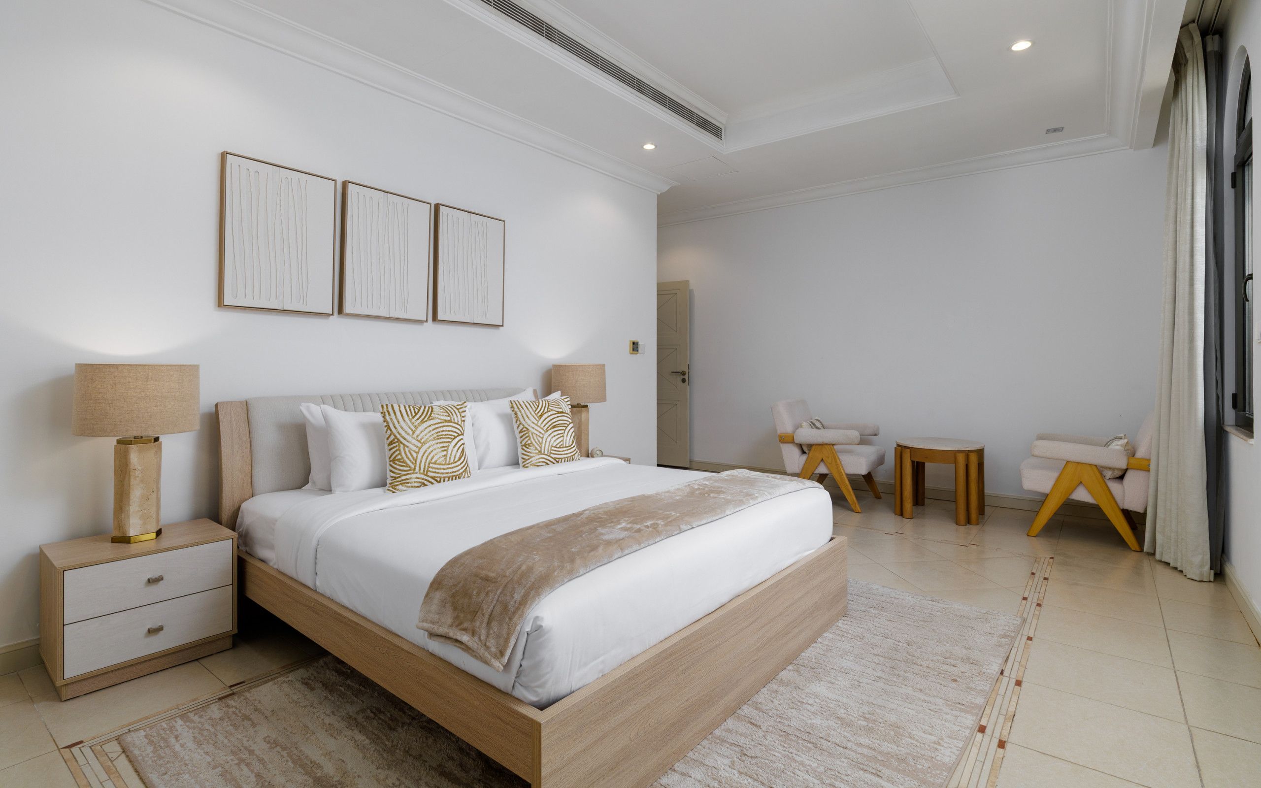 Een moderne slaapkamer met een groot bed, nachtkastjes, een bureau en een stoel.