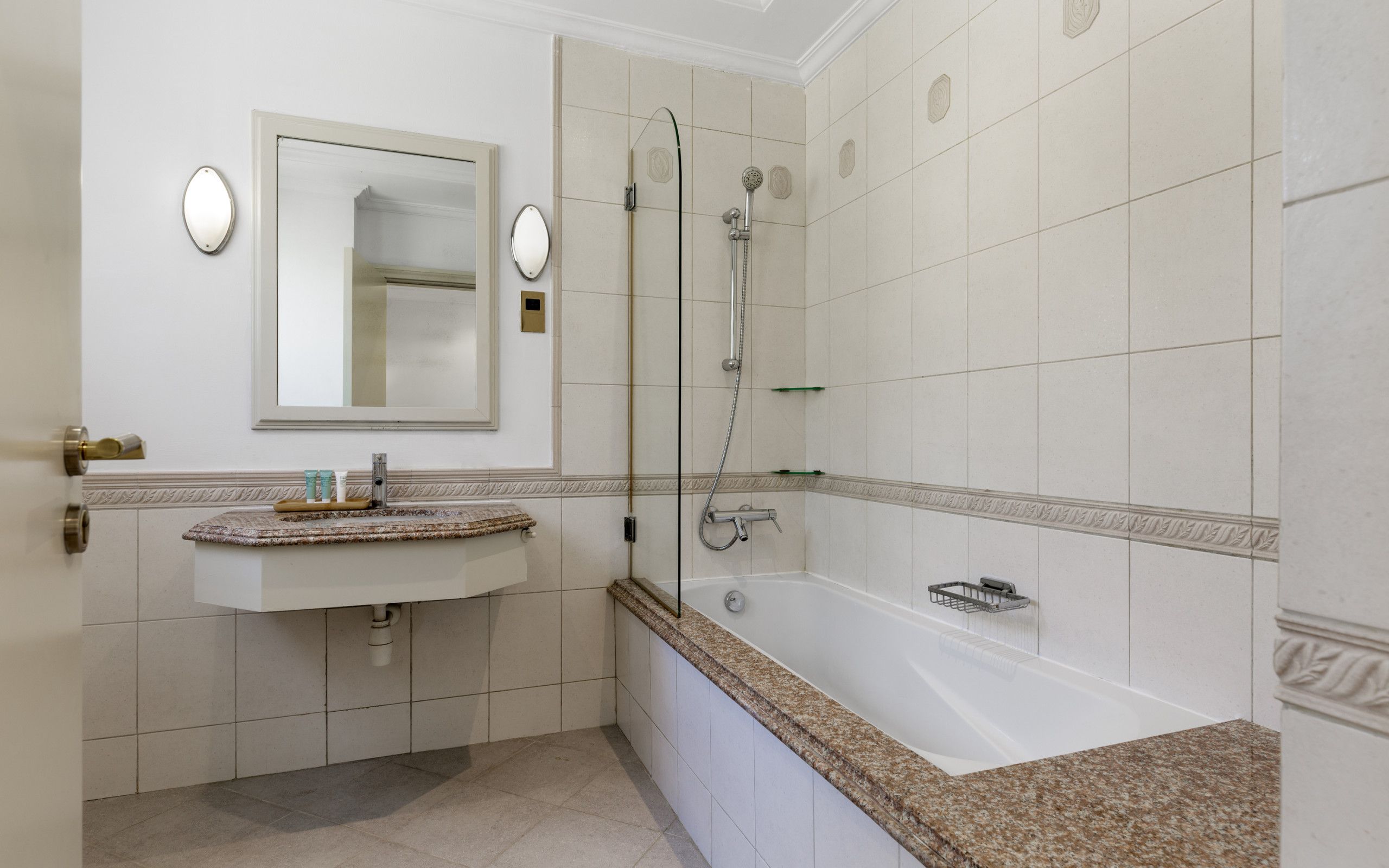 A bathroom with a sink, mirror, and shower.