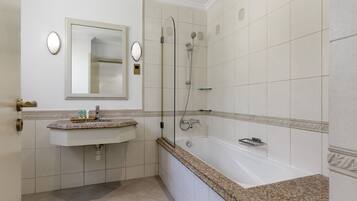 A bathroom with a sink, mirror, and shower.