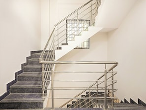 Una escalera moderna con barandillas de metal y escalones de piedra oscura.