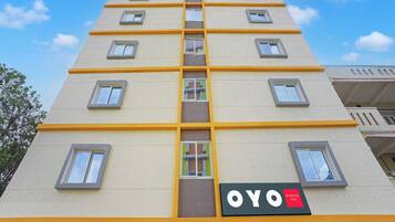 Et hotel med flere etager, hvor der hænger et tydeligt skilt med teksten 'OYO' og 'BLISSFUL STAY'.